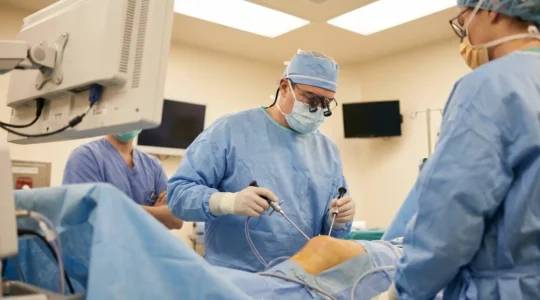 Chirurgien orthopédiste spécialisé genou au bloc opératoire, préparant une intervention de ligamentoplastie